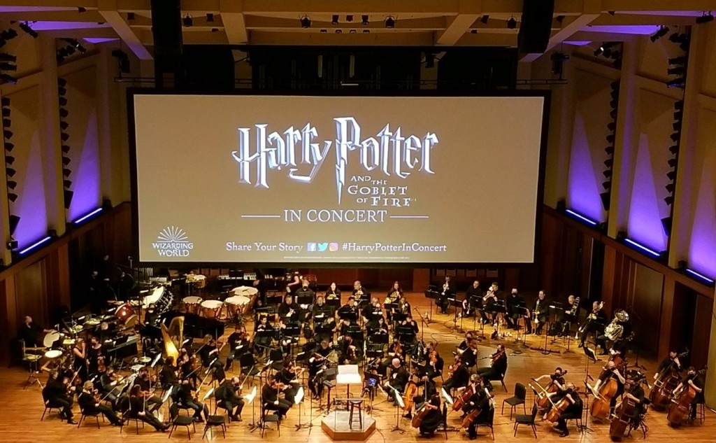 Seattle Symphony on stage, with a large screen behind him with the words "Harry Potter and the Goblet of Fire in Concert"